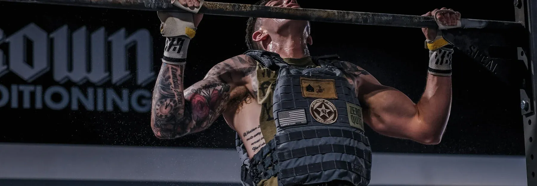An athlete grinding through weighted pull-ups at Kalamazoo Strength in Kalamazoo